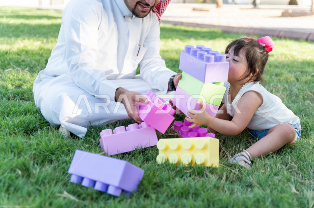A beautiful girl with Down syndrome spends her time outing with her father in the park, a Saudi Gulf father plays with his daughter outdoors, people of determination, people with special needs