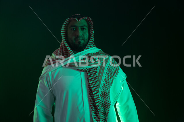 ايماءات الاعتزاز و الثقه بالنفس ، بورتريه مقرب لرجل عربي خليجي سعودي مبتسم يرتدي الثوب والشماغ التقليدي يقف باستقامة، النظر إلى الكاميرا، شخصيه سعوديه بارزه ،مفهوم الشياكه والاهتمام بالمظهر الخارجي، خلفية سوداء مع إضاءة ملونه
