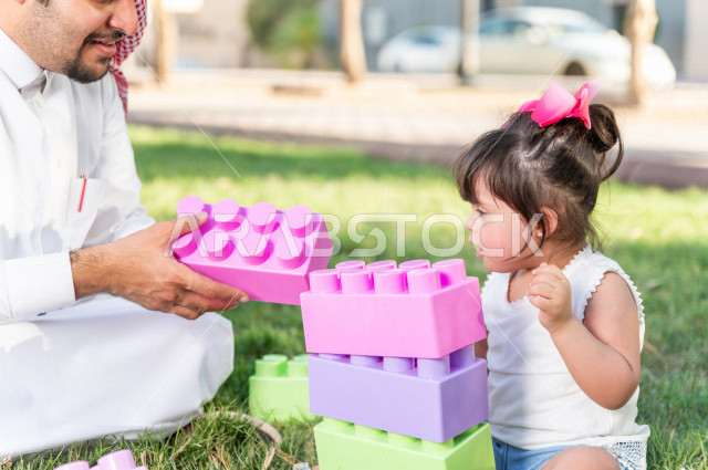 فتاه جميلة مصابة بملازمة داون تقضي وقتها في نزهه مع والدها بالمنتزه ، اب سعودي خليجي يلعب مع ابنته في الهواء الطلق ، أصحاب الهمم ، ذوي الاحتياجات الخاصة