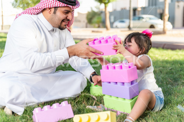 فتاه جميلة مصابة بملازمة داون تقضي وقتها في نزهه مع والدها بالمنتزه ، اب سعودي خليجي يلعب مع ابنته في الهواء الطلق ، أصحاب الهمم ، ذوي الاحتياجات الخاصة