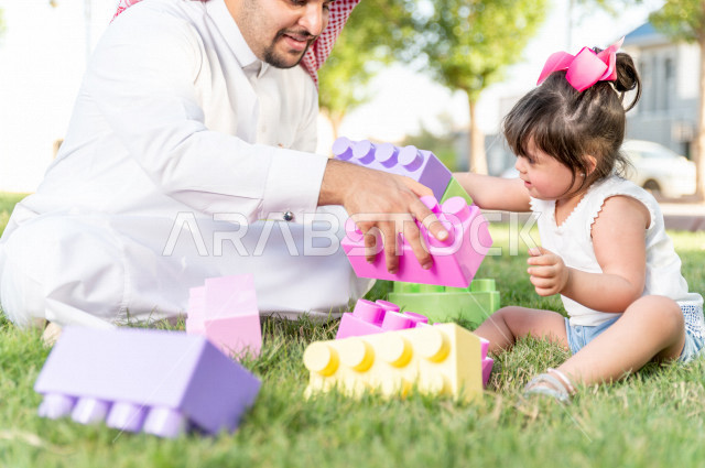 فتاه جميلة مصابة بملازمة داون تقضي وقتها في نزهه مع والدها بالمنتزه ، اب سعودي خليجي يلعب مع ابنته في الهواء الطلق ، أصحاب الهمم ، ذوي الاحتياجات الخاصة