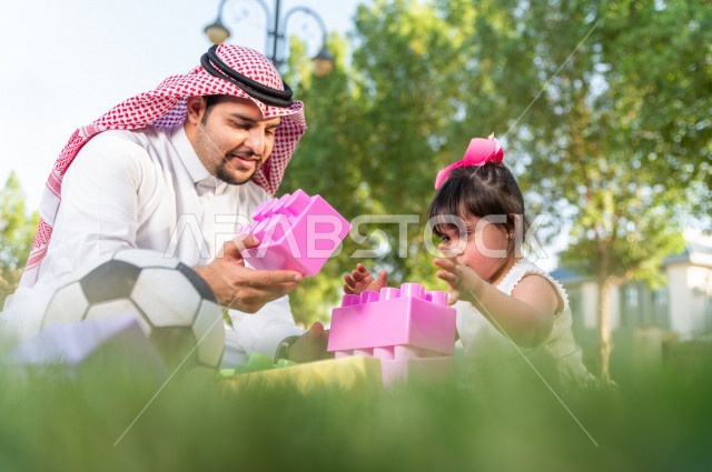 فتاه جميلة مصابة بملازمة داون تقضي وقتها في نزهه مع والدها بالمنتزه ، اب سعودي خليجي يلعب مع ابنته في الهواء الطلق ، أصحاب الهمم ، ذوي الاحتياجات الخاصة