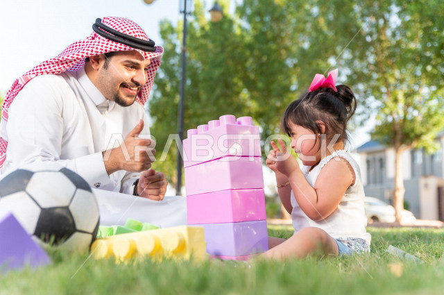 فتاه جميلة مصابة بملازمة داون تقضي وقتها في نزهه مع والدها بالمنتزه ، اب سعودي خليجي يلعب مع ابنته في الهواء الطلق ، أصحاب الهمم ، ذوي الاحتياجات الخاصة