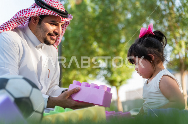 فتاه جميلة مصابة بملازمة داون تقضي وقتها في نزهه مع والدها بالمنتزه ، اب سعودي خليجي يلعب مع ابنته في الهواء الطلق ، أصحاب الهمم ، ذوي الاحتياجات الخاصة