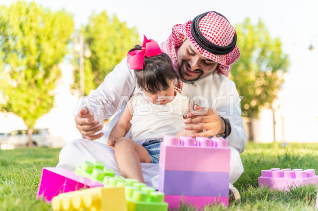 فتاه جميلة مصابة بملازمة داون تقضي وقتها في نزهه مع والدها بالمنتزه ، اب سعودي خليجي يلعب مع ابنته في الهواء الطلق ، أصحاب الهمم ، ذوي الاحتياجات الخاصة