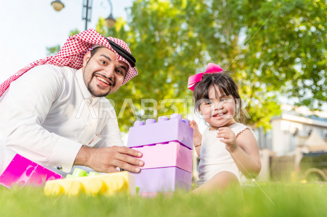 فتاه جميلة مصابة بملازمة داون تقضي وقتها في نزهه مع والدها بالمنتزه ، اب سعودي خليجي يلعب مع ابنته في الهواء الطلق ، أصحاب الهمم ، ذوي الاحتياجات الخاصة