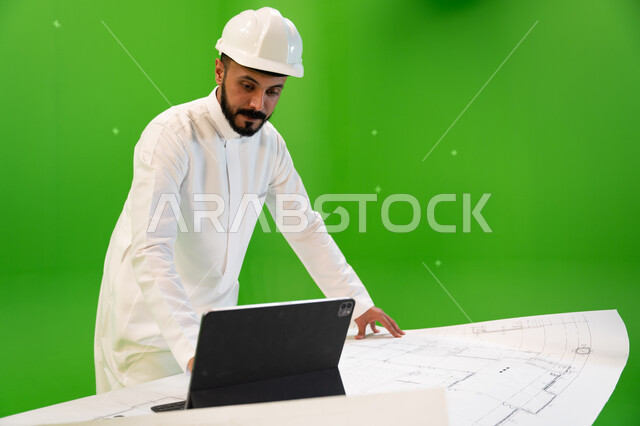إدارة شؤون الأعمال وتنظيمها, التصاميم المعمارية الحديثة عبر الجهاز المحمول, بورتريه لمهندس عربي خليجي سعودي يرتدي الثوب التقليدي وقبعة الحماية يقوم باستخدام التابليت, دمج التكنولوجيا في المجالات العملية, خلفية خضراء, كروما