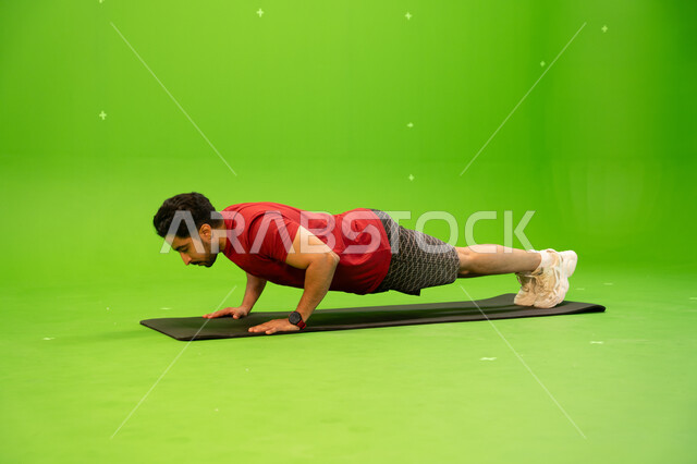 Fitness and physical health, tightening the abdominal muscles, a portrait of a Saudi Gulf Arab young man wearing sports clothing and doing exercises to maintain physical fitness, recreational youth activities and sports in the Kingdom of Saudi Arabia, gre