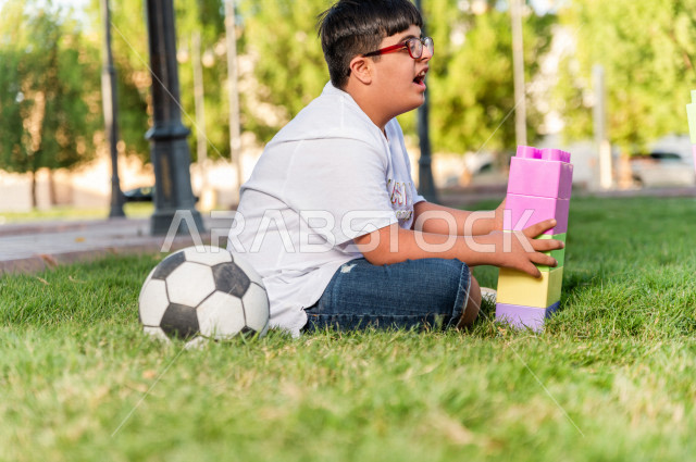 ولد سعوي خليجي مصاب بملازمة داون يقضي وقته في نزهه بالمنتزه ، يستمتع بلعب كرة القدم ، أصحاب الهمم ، ذوي الاحتياجات الخاصة