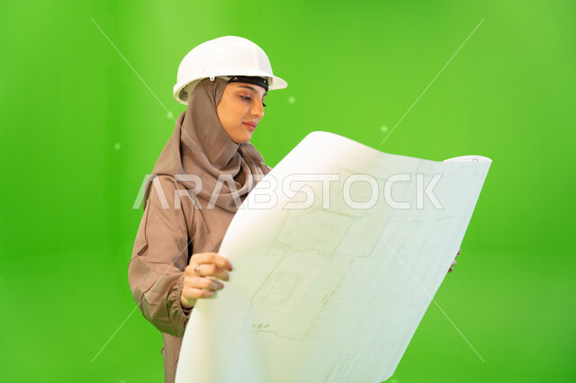 التدقيق والإشراف على العمل، التحقق من تنفيذ المشاريع الإنشائية , مفهوم الهندسة والإنشاءات المعمارية، بورتريه مقرب من الجانب لمهندسة عربية خليجية سعودية محجبة ترتدي العباءة السعودية و خوذة الحماية وتمسك بيدها مخططات وتصاميم هندسية، كروما، خلفية خضراء