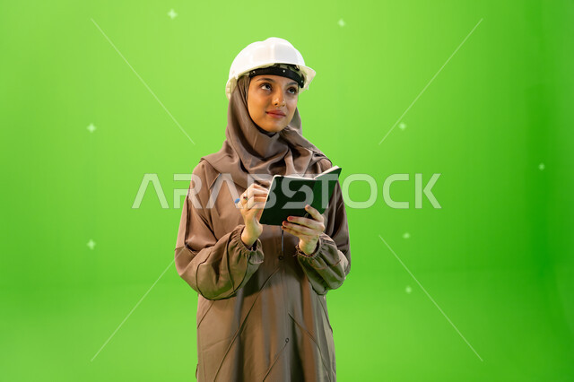 متابعة سير المشروع في موقع العمل, بورتريه مقرب لمهندسة عربية خليجية سعودية محترفة ترتدي العباءة السعودية و خوذة الحماية وتقوم بكتابة وتدوين الملاحظات، إدارة ودراسة المشاريع الهندسية، الإشراف على العمل وتدقيقه، خلفية خضراء, كروما