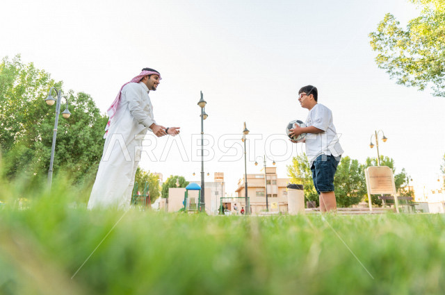 فتى شاب مصاب بملازمة داون يقضي وقته في نزهه مع والده بالمنتزه ، اب سعودي خليجي يلعب مع ابنه بكرة القدم ، أصحاب الهمم ، ذوي الاحتياجات الخاصة