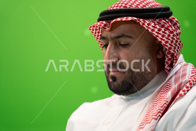 الاهتمام بالمظهر الخارجي , بورتريه مقرب من الجانب لرجل عربي خليجي سعودي يرتدي الشماغ والعقال وينظر للأسفل, ارتداء الثوب السعودي التقليدي, رجل خليجي أنيق, خلفية خضراء , كروما