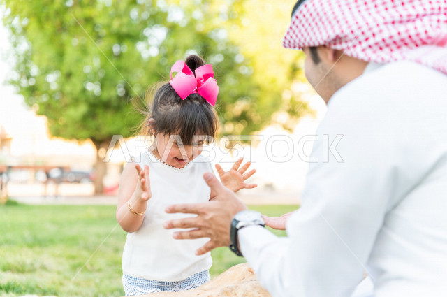 فتاه جميلة مصابة بملازمة داون تقضي وقتها في نزهه مع والدها بالمنتزه ، اب سعودي خليجي يلعب مع ابنته في الهواء الطلق ، أصحاب الهمم ، ذوي الاحتياجات الخاصة