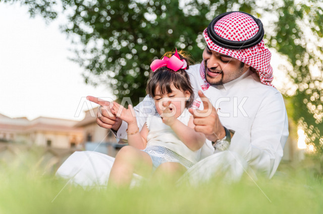 فتاه جميلة مصابة بملازمة داون تقضي وقتها في نزهه مع والدها بالمنتزه ، اب سعودي خليجي يلعب مع ابنته في الهواء الطلق ، أصحاب الهمم ، ذوي الاحتياجات الخاصة