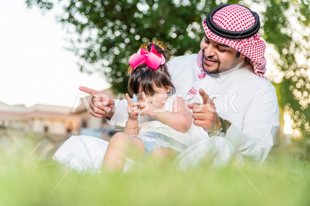 فتاه جميلة مصابة بملازمة داون تقضي وقتها في نزهه مع والدها بالمنتزه ، اب سعودي خليجي يلعب مع ابنته في الهواء الطلق ، أصحاب الهمم ، ذوي الاحتياجات الخاصة