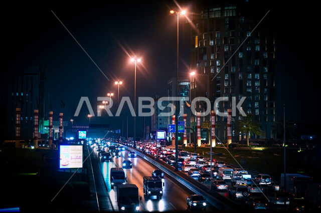 حركة سير السيارات على الطريق العام في مدينة الرياض، لوحات إعلانية إلكترونية على جوانب الطرق والشوارع، أعمدة الإنارة المضيئة في الليل، وسائل النقل والمواصلات في المملكة العربية السعودية