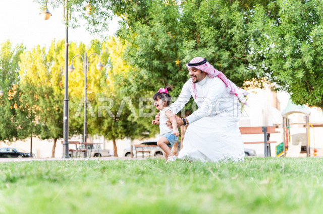 فتاه جميلة مصابة بملازمة داون تقضي وقتها في نزهه مع والدها بالمنتزه ، اب سعودي خليجي يلعب مع ابنته في الهواء الطلق ، أصحاب الهمم ، ذوي الاحتياجات الخاصة