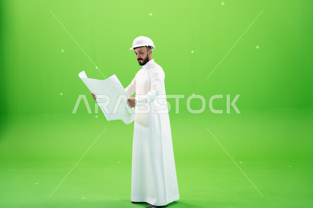 المشاريع الإعمارية التنموية في المملكة, دعم وتنمية القطاع الهندسي, بورتريه من الجانب لمهندس عربي خليجي سعودي يرتدي الثوب التقليدي وقبعة الحماية يقف في موقع العمل ويحمل بيده المخطط التنفيذي, صورة الجسم بالطول الكامل, خلفية خضراء, كروما