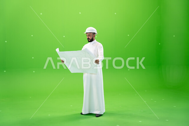 المشاريع الإعمارية التنموية في المملكة, دعم وتنمية القطاع الهندسي, بورتريه من الجانب لمهندس عربي خليجي سعودي يرتدي الثوب التقليدي وقبعة الحماية يقف في موقع العمل ويحمل بيده المخطط التنفيذي, صورة الجسم بالطول الكامل, خلفية خضراء, كروما