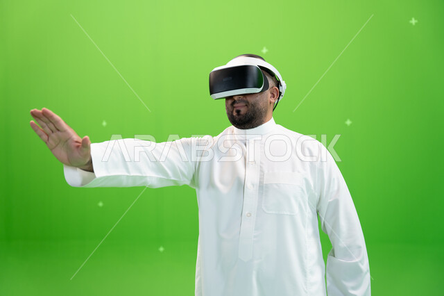 الاندماج والتفاعل مع العالم الخيالي , قضاء أوقات ممتعة مع ألعاب الواقع الافتراضي, دفع عنصر هولوجرامي، بورتريه مقرب  لرجل عربي خليجي سعودي يرتدي الزي التقليدي و نظارة الواقع الإفتراضي ثلاثية الأبعاد، خلفية خضراء، كروما
