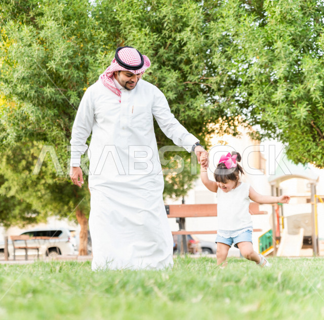 فتاه جميلة مصابة بملازمة داون تقضي وقتها في نزهه مع والدها بالمنتزه ، اب سعودي خليجي يلعب مع ابنته في الهواء الطلق ، أصحاب الهمم ، ذوي الاحتياجات الخاصة