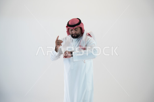 تتبع اشعارات التذكير باستخدام التقنيات الحديثة في الساعات الذكية , إيماءات النظر الى الساعة وتذكر موعد مهم, بورتريه لرجل عربي خليجي سعودي يرتدي الشماغ والثوب التقليدي ويلبس في يده ساعة ذكية ويقوم بمتابعتها, خلفية بيضاء