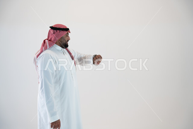 تتبع اشعارات التذكير باستخدام التقنيات الحديثة في الساعات الذكية , إيماءات النظر الى الساعة وضبط المواعيد, بورتريه من الجانب لرجل عربي خليجي سعودي يرتدي الشماغ والثوب التقليدي ويلبس في يده ساعة ذكية ويقوم بمتابعتها, خلفية بيضاء