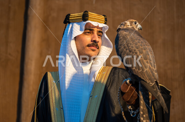 شغف السعوديين بتربية الطيور الجارحة, النظر الى الصقر بإيماءات القوة والتحدي, التمسك بموروث المملكة الحضاري والثقافي, صورة مقربة لرجل عربي خليجي سعودي يرتدي الغترة والبشت والعقال يحمل على يده طائر الصقر, علاقة الصقور تأسيس المملكة 22 فبراير, يوم التأسيس 1727
