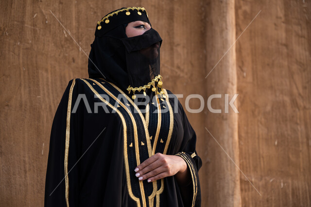 تأسيس الدولة السعودية الأولى 1727 م، ارتداء أزياء المنطقة الوسطى في المناسبات الوطنة، مفهوم الاهتمام والعناية بالمظهر الخارجي، صورة مقربة لإمرأة خليجية عربية سعودية ترتدي العباءة السوداء والبرقع، يوم التأسيس في 22 فبراير، الوقوف بفخر وثقة والنظر الى شيء ما