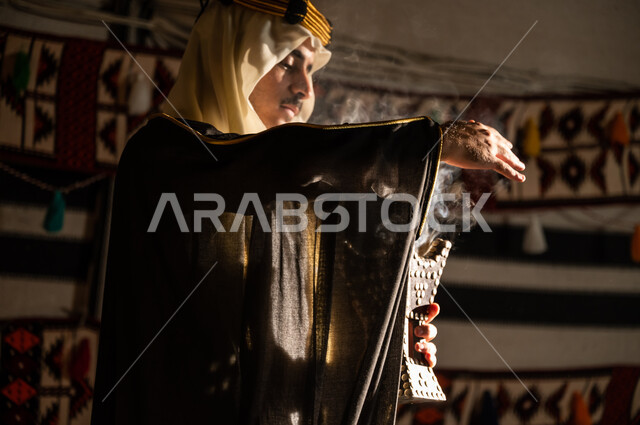 التجهز للاحتفال بيوم التأسيس 1727م, استخدام المنتجات العطرية المحلية, تأسيس الدولة السعودية الأولى 22 فبراير, استعمال خشب العود للتعطر بالبخور، صورة مقربة من الجانب لرجل عربي خليجي سعودي يرتدي الغترة والبشت يقوم بتبخير نفسه باستخدام المبخرة