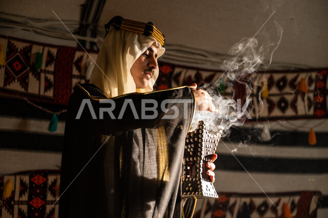 استخدام المنتجات العطرية المحلية, تأسيس الدولة السعودية الأولى 22 فبراير, التجهز للاحتفال بيوم التأسيس 1727م, استعمال خشب العود للتعطر بالبخور، صورة مقربة من الجانب لرجل عربي خليجي سعودي يرتدي الغترة والبشت يقوم بتبخير نفسه باستخدام المبخرة