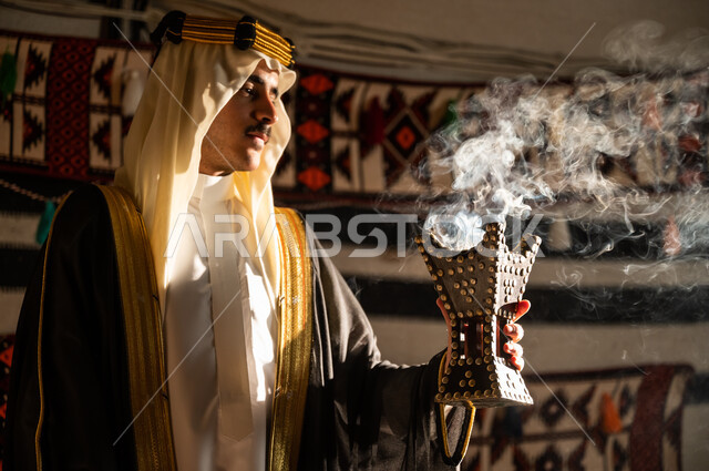 استعمال خشب العود للتعطر بالبخور، التبخر والتطيب للاحتفال بيوم التأسيس 22 فبراير, روائح عطرية سعودية مميزة, صورة مقربة من الجانب لرجل عربي خليجي سعودي يرتدي الغترة والبشت يقوم بتبخير نفسه باستخدام المبخرة, تأسيس السعودية 1727م, اتباع موروث الأجداد وعاداتهم