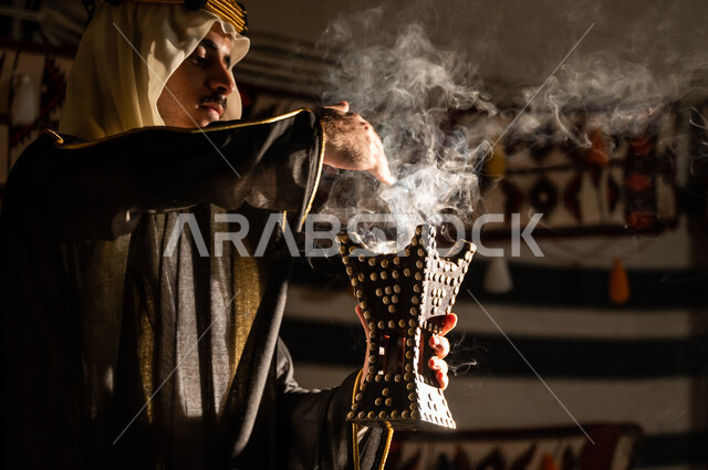 عراقة وأصالة العادات والتقاليد السعودية, استخدام خشب العود للتطيب بالبخور، ارتداء الأزياء الشعبية في يوم التأسيس 1727, صورة مقربة من الجانب لرجل عربي خليجي سعودي يرتدي الغترة والبشت يقوم بالتعطر باستخدام المبخرة, تأسيس الدولة السعودية الأولى 22 فبراير
