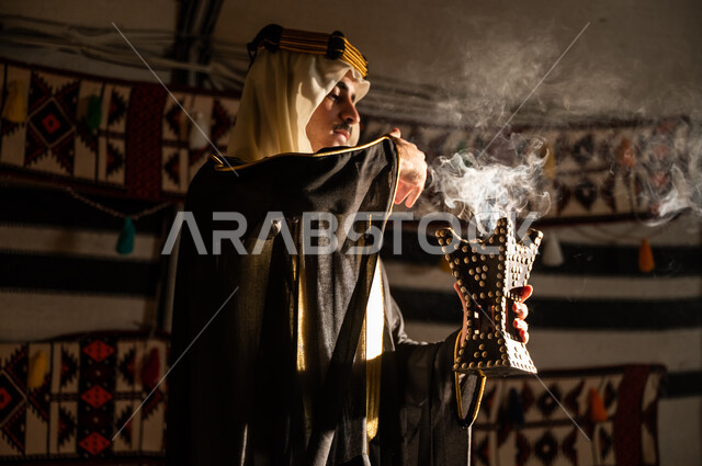 عراقة وأصالة العادات والتقاليد السعودية, استخدام خشب العود للتطيب بالبخور، ارتداء الأزياء الشعبية في يوم التأسيس 1727, صورة مقربة من الجانب لرجل عربي خليجي سعودي يرتدي الغترة والبشت يقوم بالتعطر باستخدام المبخرة, تأسيس الدولة السعودية الأولى 22 فبراير