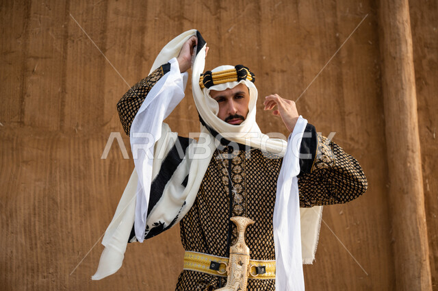 Wearing popular costumes and belts, pride in owning the traditional jambiya, taking care of the external appearance, anniversary of the founding of the Kingdom in 1727, highlighting the spirit of belonging to the homeland, a close-up of a Saudi Gulf Arab man wearing the dhokla and the golden aqal and adjusting the ghutra, Founding Day, February 22