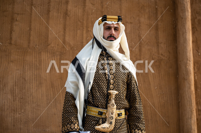 ارتداء الجنبية في يوم التأسيس 1727, مشاعر الفخر بالانتماء للوطن, صورة مقربة لرجل عربي خليجي سعودي يرتدي الدقلة و الغترة مع المحزم والخنجر يقف بثقة ويقوم بالنظر الى شيء ما, تأسيس الدولة السعودية الأولى ٢٢ فبراير, الاعتزاز بامتلاك الخناجر الوطنية التراثية