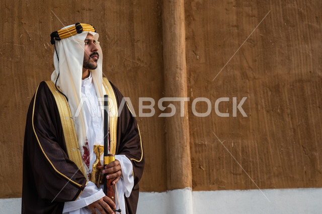 Passion for practicing the hobby of falcon hunting, following the legacy of our ancestors and celebrating their achievements, standing with confidence and pride and looking at something, a Saudi Gulf Arab man wearing a bisht, a ghutra, and a golden headband and holding a rifle in his hand, the founding of the first Saudi state in 1727 AD, founding day February 22