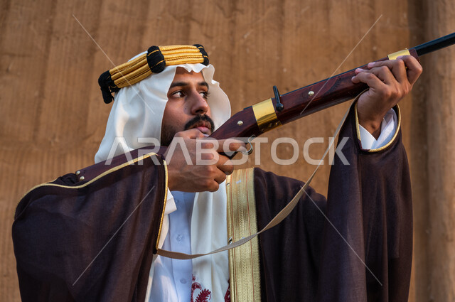 إقامة نادي الصقور في المملكة في ذكرى تأسيس الدولة الأولى 1727, استخدام البندقية لقنص الحيوانات البرية, صورة مقربة لشاب عربي خليجي سعودي يرتدي الغترة والبشت ويقوم بصيد الطيور الجارحة, التعيين والتركيز على الهدف, براعة السعوديين في الصيد, يوم التأسيس 22 فبراير