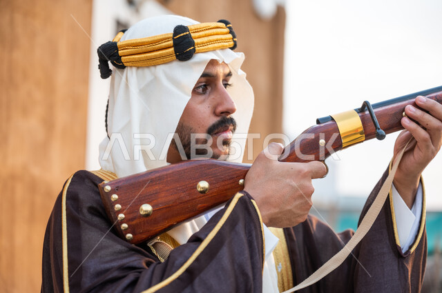 ذكرى يوم التأسيس 22 فبراير, استخدام البندقية لقنص الحيوانات البرية, صورة مقربة لشاب عربي خليجي سعودي يرتدي الغترة والعقال الذهبي ويقوم بصيد الطيور الجارحة, التركيز على الهدف بدقة, تأسيس الدولة السعودية الأولى 1727, براعة السعوديين في الصيد