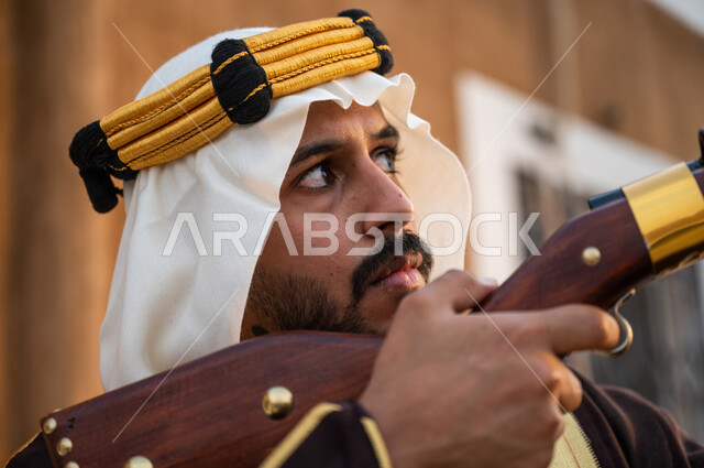 تأسيس الدولة السعودية الأولى 1727, استخدام البندقية لقنص الحيوانات البرية, صورة مقربة لشاب عربي خليجي سعودي يرتدي الغترة والعقال الذهبي ويقوم بصيد الطيور الجارحة, التركيز على الهدف بدقة, ذكرى يوم التأسيس 22 فبراير, براعة السعوديين في الصيد
