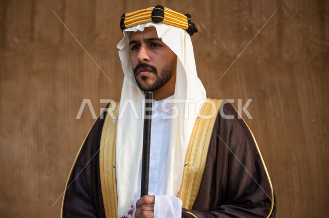 اهتمام أبناء المملكة بهواية صيد الصقور، ارتداء الأزياء الشعبية الوطنية, إحياء تاريخ الأجداد والاحتفال بإنجازاتهم, صورة مقربة لرجل عربي خليجي سعودي يرتدي البشت والغترة يحمل البندقية بفخر وينظر الى شيء ما، الاحتفال بيوم التأسيس 22 فبراير، ذكرى تأسيس المملكة 1727