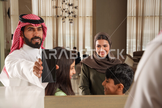  تأكيد الحجز الفندقي لموظف الاستقبال عبر الجوال, الحجوزات الالكترونية للفنادق وتذاكر السفر عبر الهاتف المحمول, عائلة عربية سعودية خليجية في إحدى الفنادق الفاخرة, عرض شاشة سوداء فارغة, ايماءات السعادة والسرور