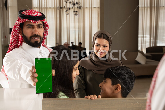 ايماءات السعادة والسرور, الحجوزات الالكترونية للفنادق وتذاكر السفر عبر الهاتف المحمول, تأكيد الحجز الفندقي لموظف الاستقبال عبر الجوال, عائلة عربية سعودية خليجية في إحدى الفنادق الفاخرة, عرض شاشة خضراء فارغة, كروما