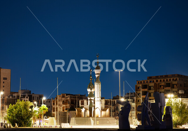 دوار جده البلد في حي البلد، معلم تاريخي أثري  قديم، الفن الهندسي المعماري للمجسمات الأثرية، الاشجار والنباتات الخضراء مع ضوء أعمدة الانارة في الليل، أماكن سياحية في السعودية
