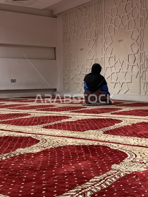 الطاعة والعبادة والتقرب إلى الله عن طريق القيام بالعبادات، صورة من الخلف لإمرأة عربية خليجية سعودية تقوم بأداء الفرائض في المسجد، التضرع والخشوع أثناء الصلاة، إصلاح النفس بالتذلل لرب العالمين, اسلاميات وعبادة