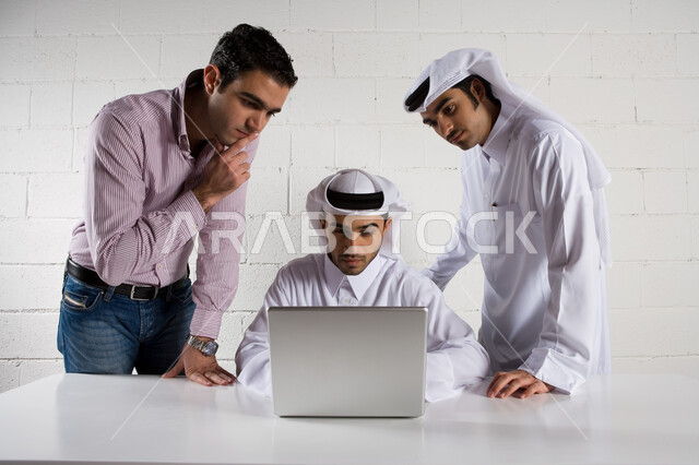  المقاولات والاستثمار في دول الخليج العربي ، رجال أعمال عرب إماراتيون خليجيون  في اجتماع عمل في مقر الشركة ، النقاش والحوار حول أهداف الشركة   ،   تقديم الأفكار وشرح تفاصيل وثغرات المشروع  في المكتب  ، إيماءات النظر الى شاشة جهاز الحاسوب المحمول .