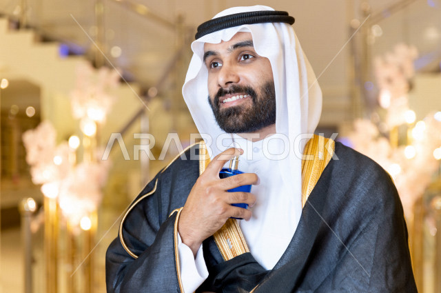 معرس شاب سعودي خليجي يقوم بوضع العطر ، حفلة الزفاف ، ليلة العمر ، عريس بالزي السعودي الرسمي ، مناسبات الزواج