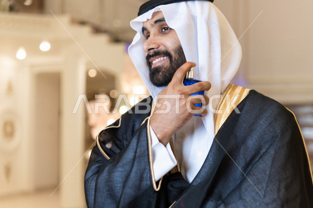 معرس شاب سعودي خليجي يقوم بوضع العطر ، حفلة الزفاف ، ليلة العمر ، عريس بالزي السعودي الرسمي ، مناسبات الزواج