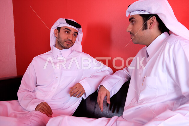 Discussions, dialogues and new business agreements, two Arab Gulf and Emirati businessmen wearing traditional clothing and sitting at the company’s headquarters, studying and analyzing newly proposed projects, cooperation between companies to obtain the best deals, discussing and following up on the company’s goals